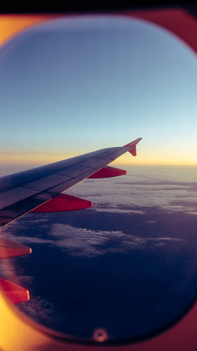 Blick aus dem Flugzeugfenster: Flügel gegen einen blauen Himmel und Horizont