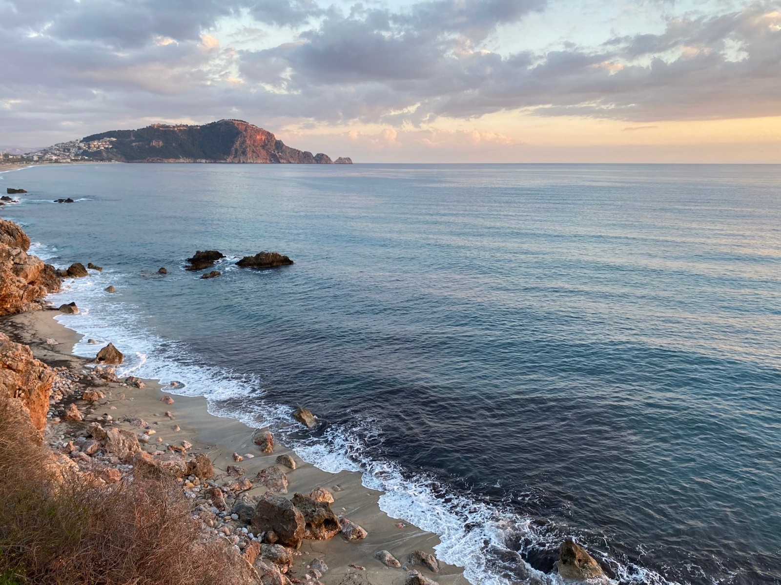 Arafed view of a rocky beach with a cliff and a body of water (kleopatra beach, physics, science, water, cloud)