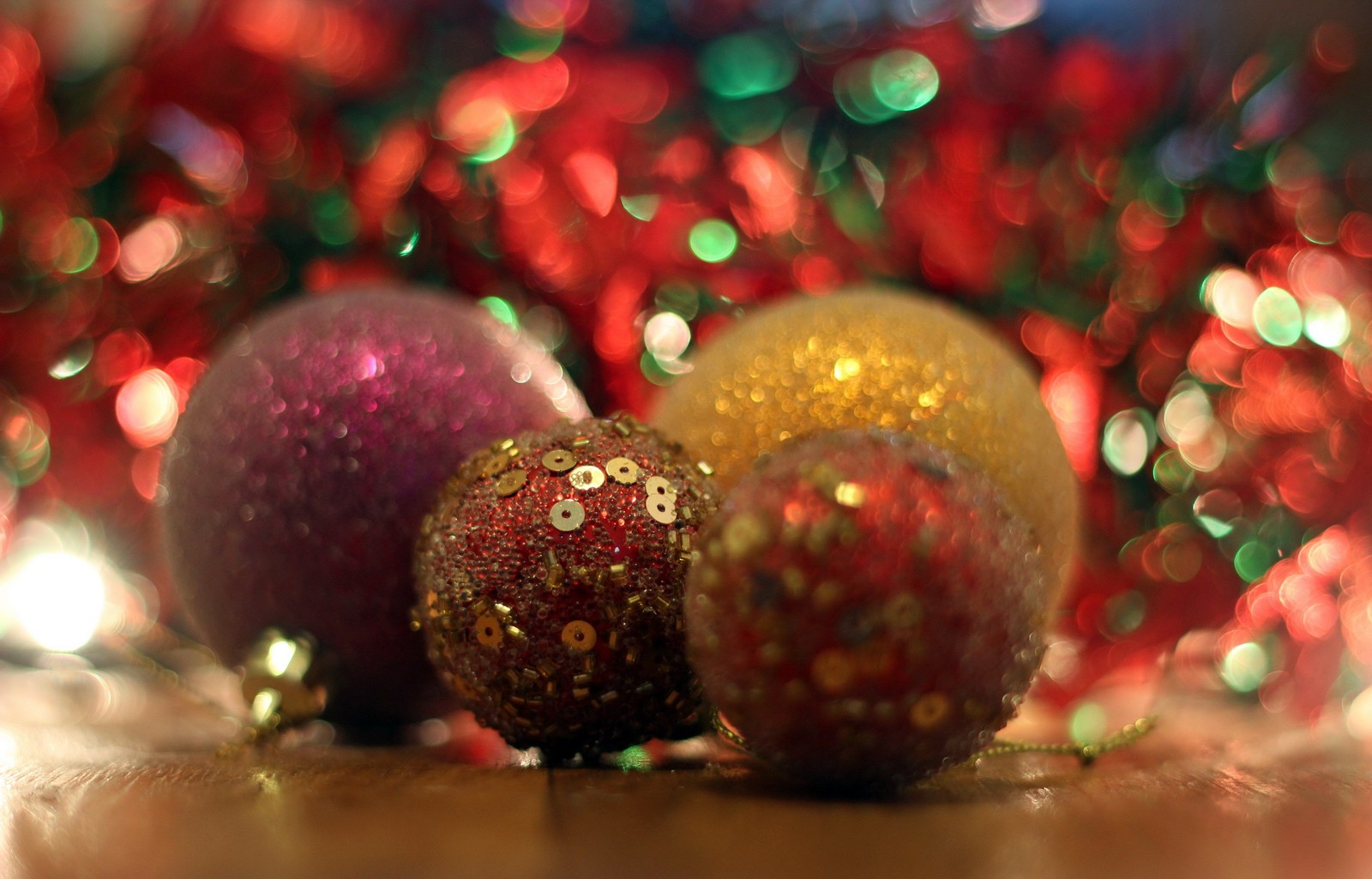 Há três bolas de natal em uma mesa com uma árvore de natal ao fundo (ornamento de natal, dia de natal, feriado, brilho, enfeite de natal)