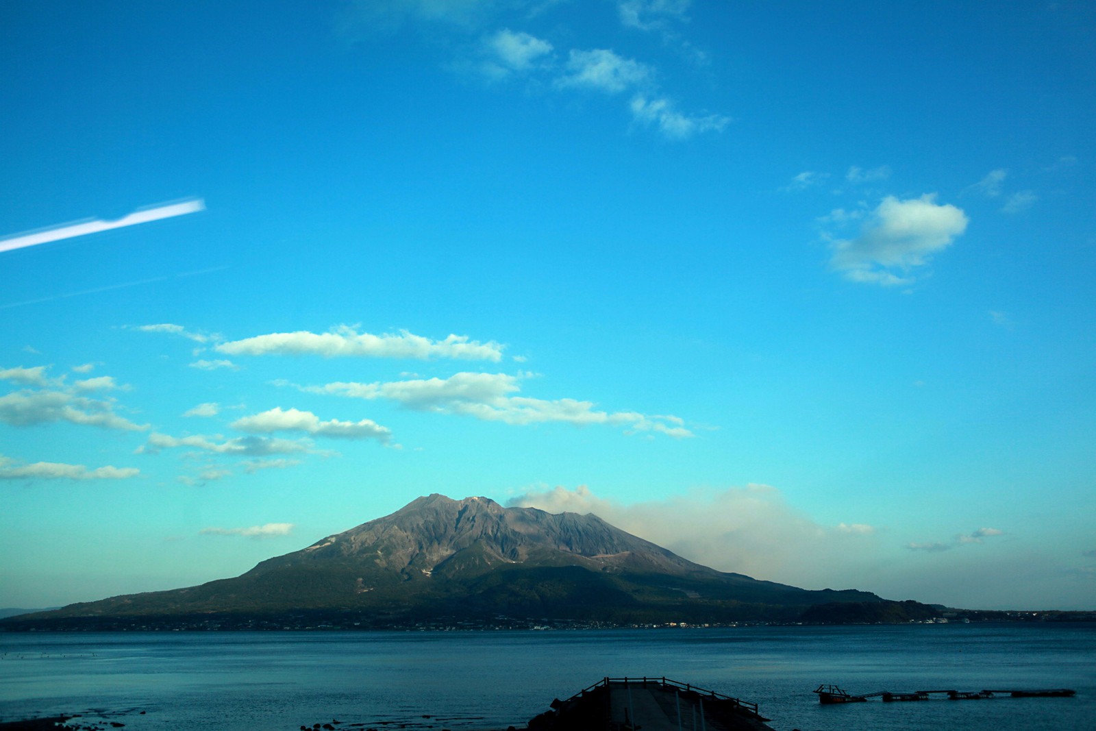 Une montagne au loin avec un avion volant au-dessus (nuage, mer, horizon, océan, décor montagnard)