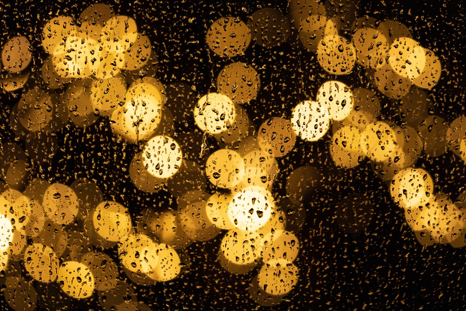 Gros plan d'une fenêtre avec des gouttes de pluie dessus (bokeh, jaune, motif, design, nuit)