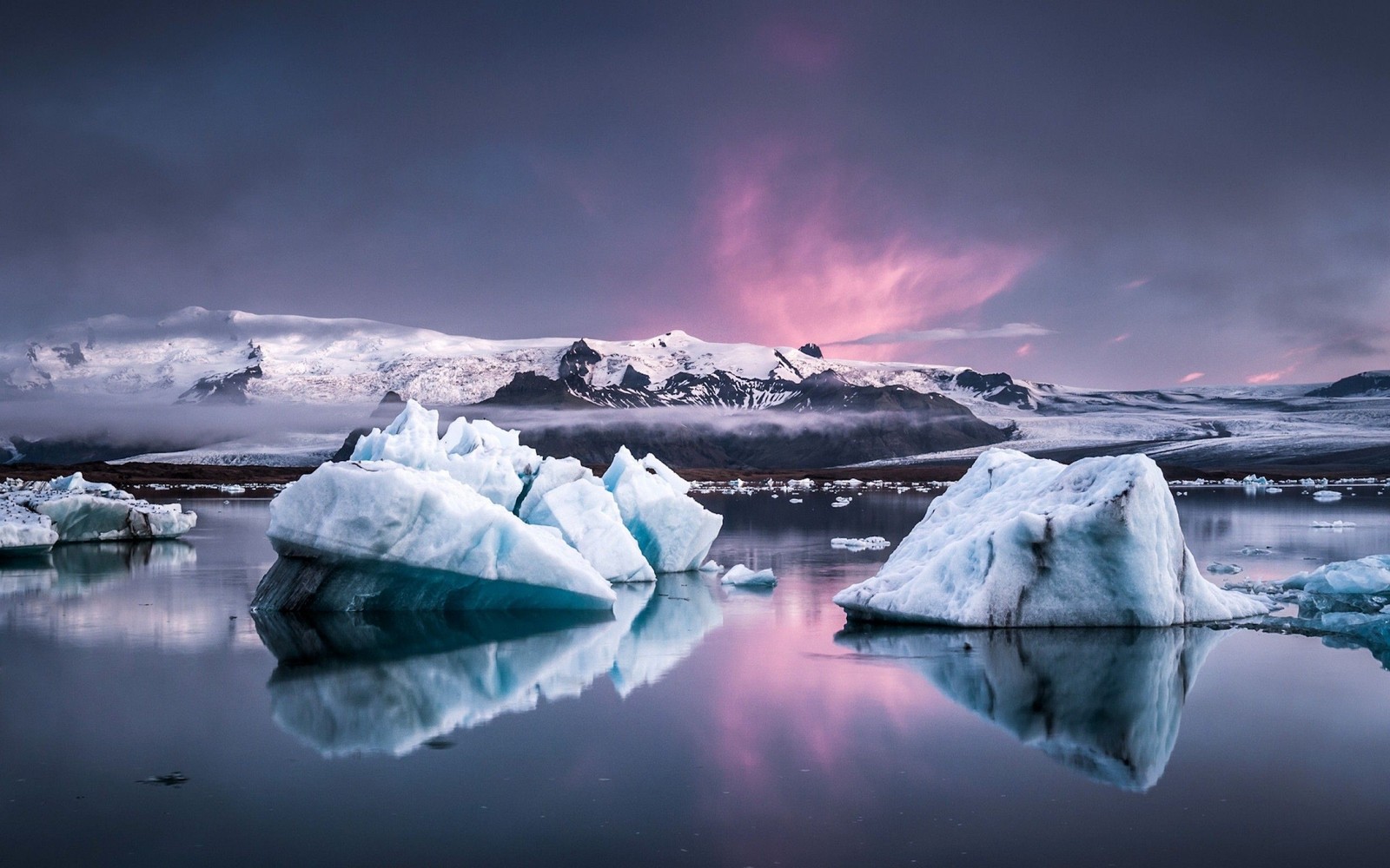 Un grupo de icebergs flotando en un lago con montañas al fondo (iceberg, naturaleza, hielo, hielo marino, lago glaciar)