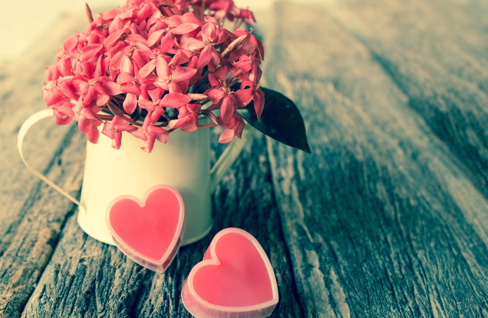 Il y a deux bougies en forme de cœur dans un vase sur une table (saint valentin, rose, fleur, amour, pétale)