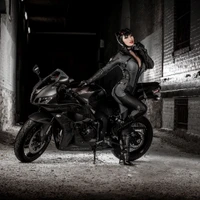 Black-clad Biker Girl Posing with Sleek Motorcycle