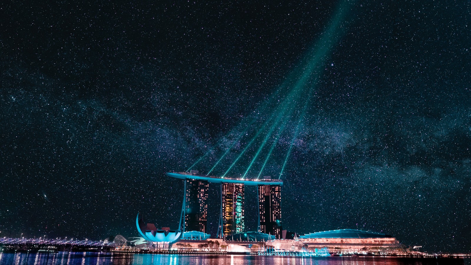 Uma vista do horizonte da cidade à noite com um feixe de luz brilhante no céu (marina bay sands, cidade noturna, hotel, singapura, estrelas)