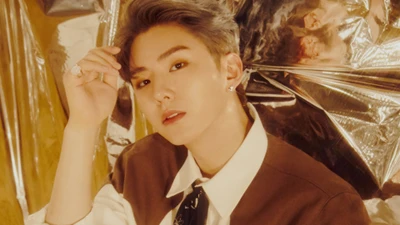 Kihyun of Monsta X in a stylish pose against a shimmering backdrop.