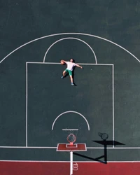 Vista aérea de una cancha de baloncesto con un jugador acostado en la cancha, enfatizando el deporte y sus líneas vibrantes.