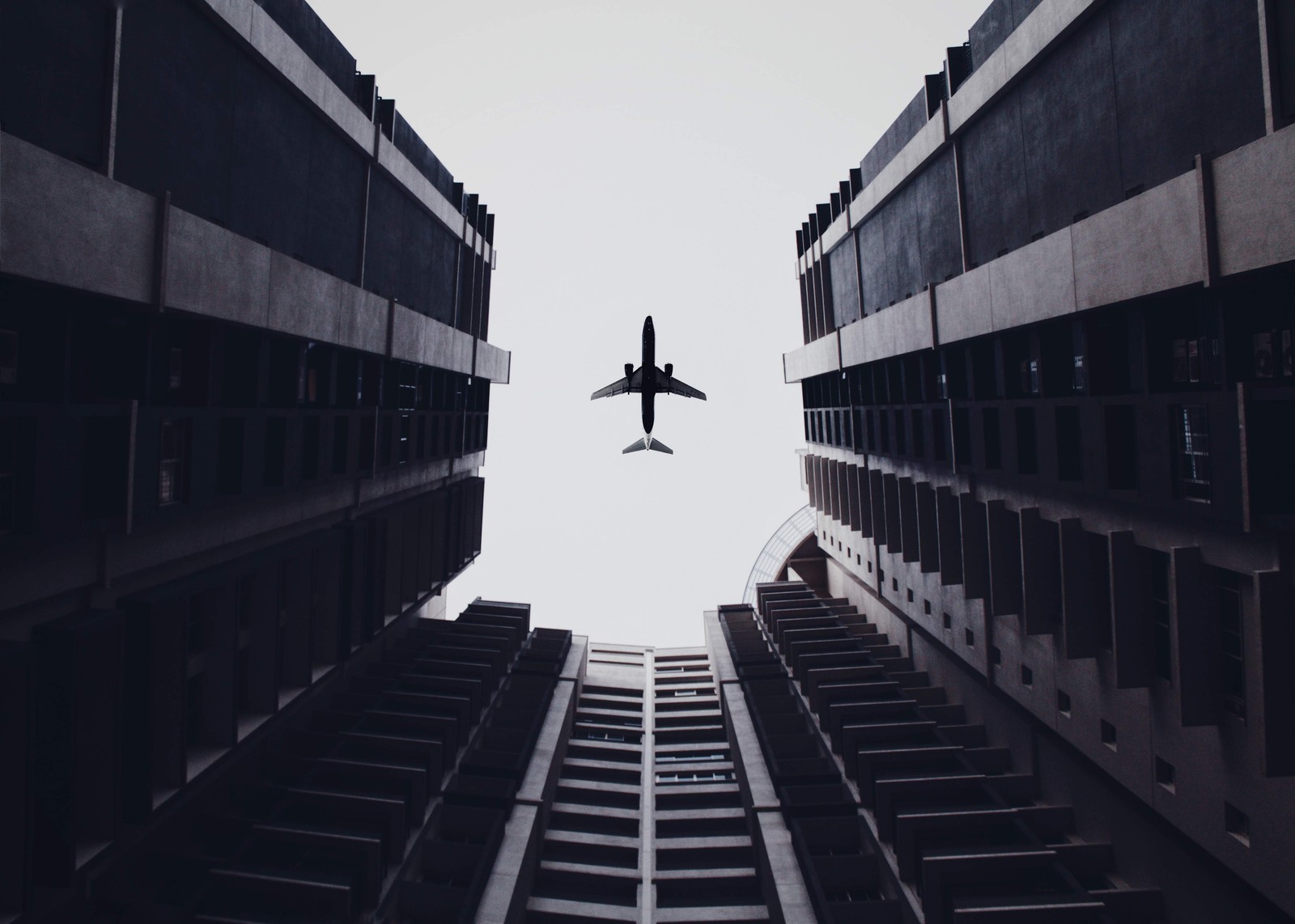 Un avion survolant un bâtiment dans le ciel (avion, blanc, noir, architecture, monochrome)