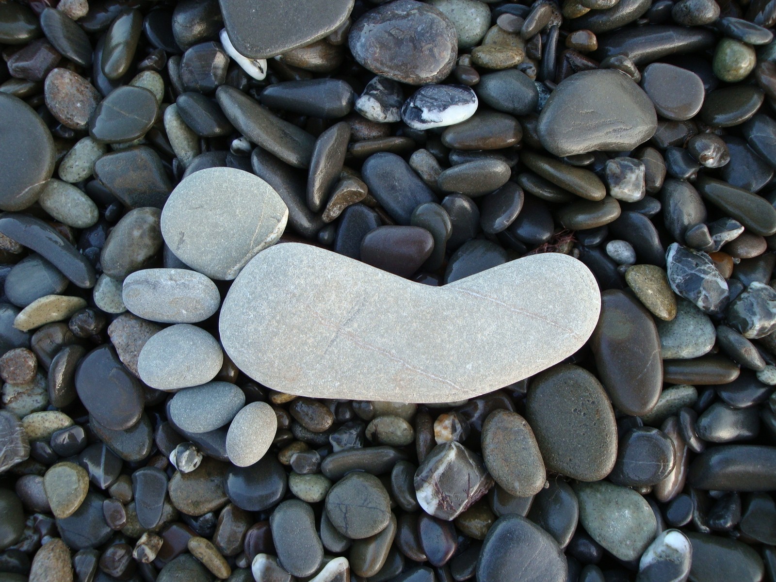 A close up of a stone with a smiley face on it (pebble, rock, gravel, material)