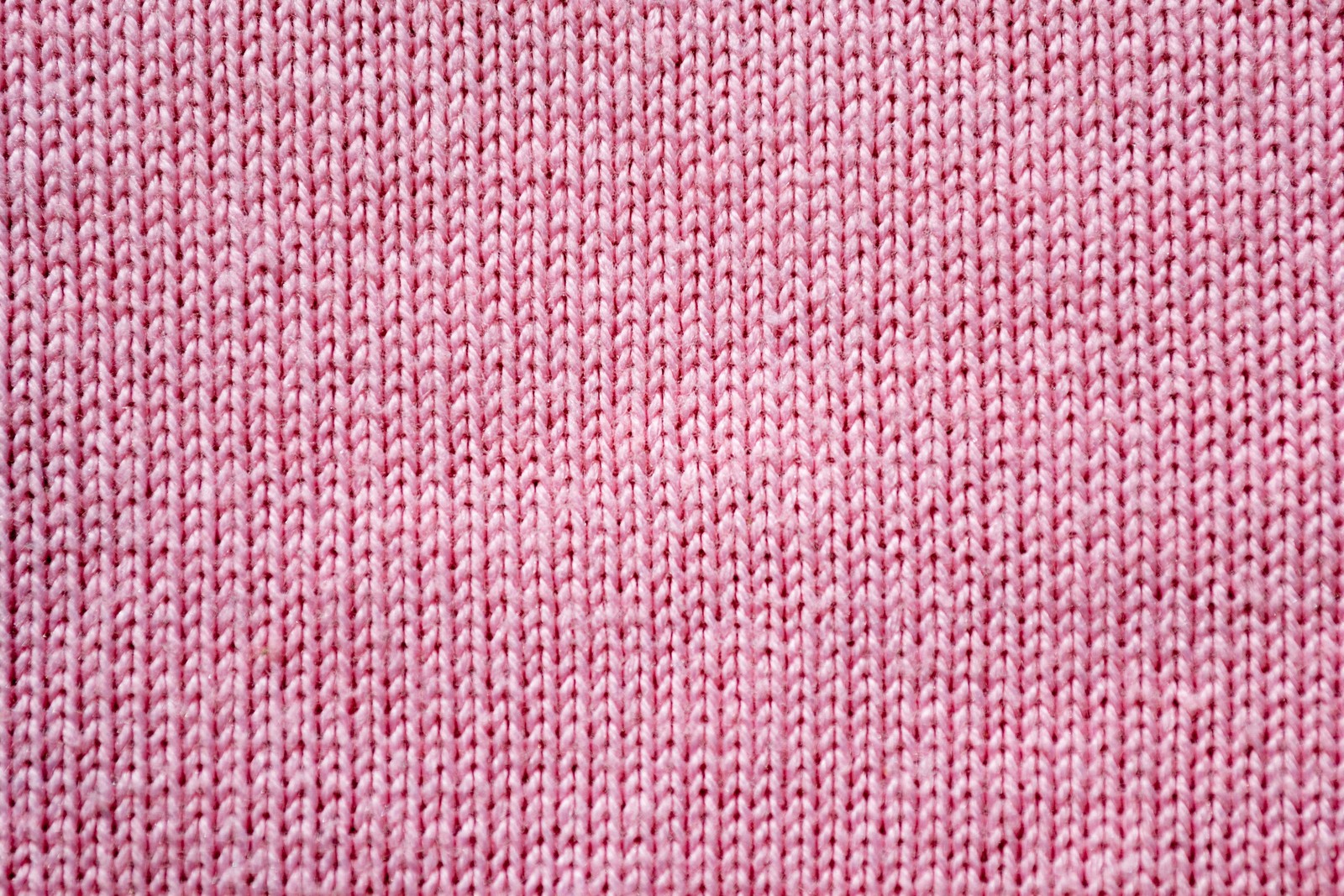 A close up of a pink knitted cloth with a small hole (textile, pink, weaving, woolen, woven fabric)