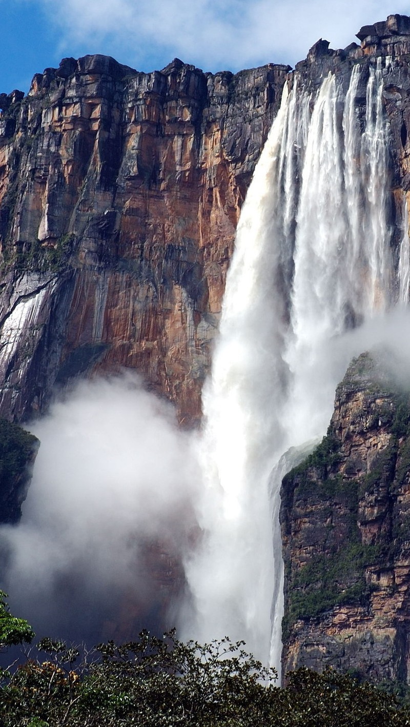 Uma girafa cai em uma grande cachoeira com um céu azul ao fundo (montanha, água, cachoeira)