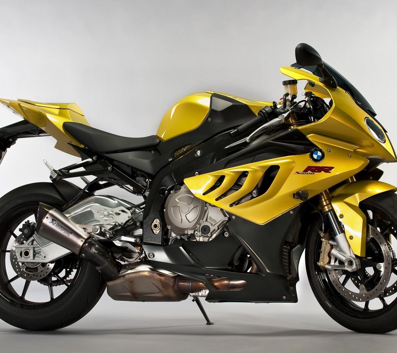 A close up of a yellow motorcycle parked on a white surface (motorbike, vehicles)