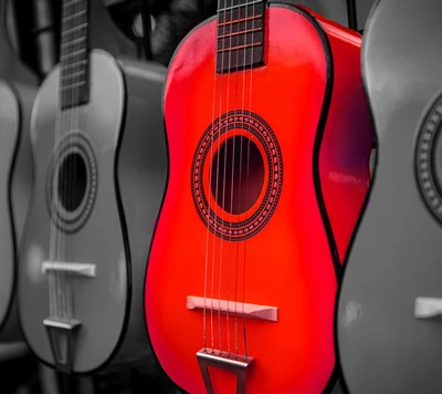 Guitarra acústica roja vibrante entre instrumentos monocromáticos