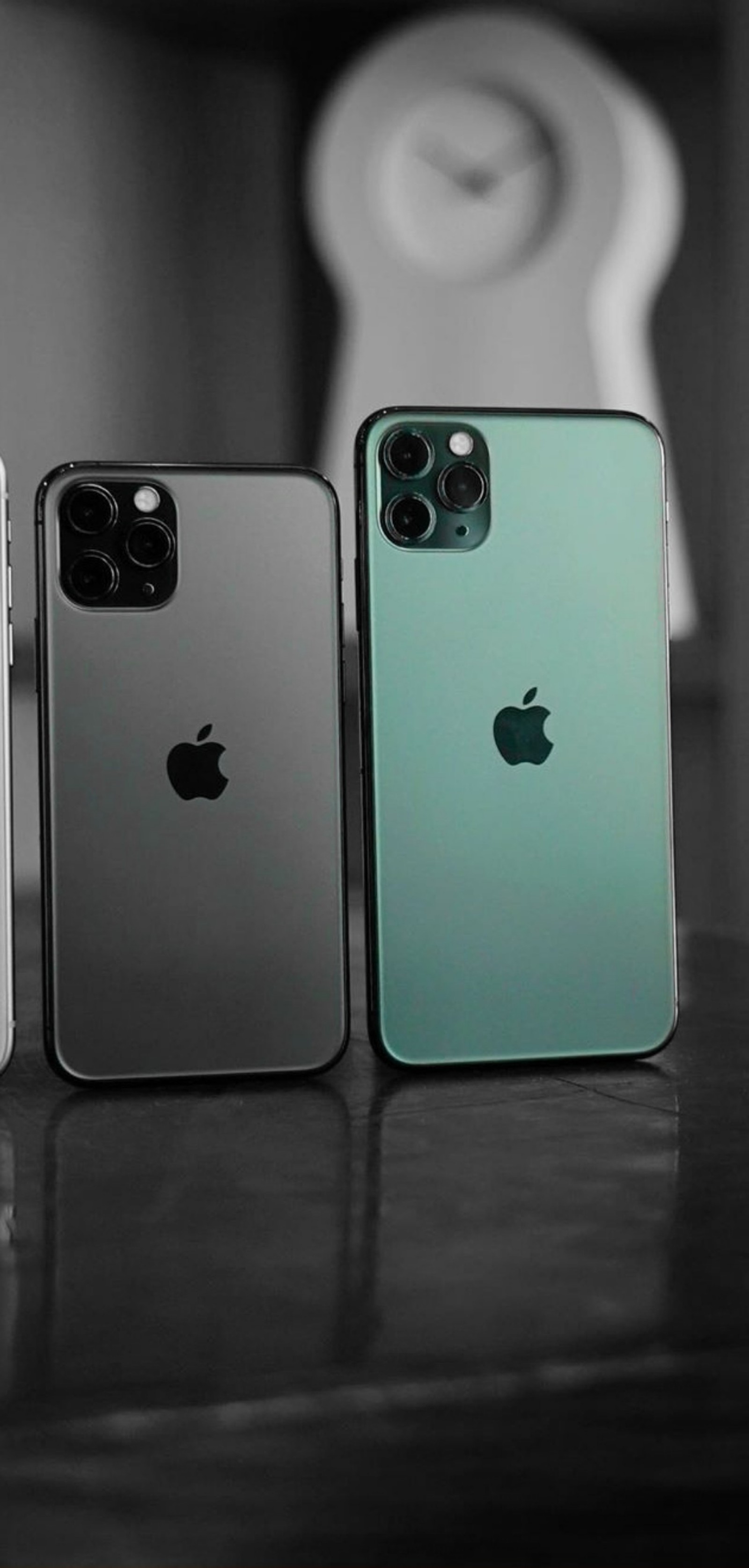 Tres iphones están sobre una mesa con un reloj al fondo (iphone 11, iphone 11 pro, amor)