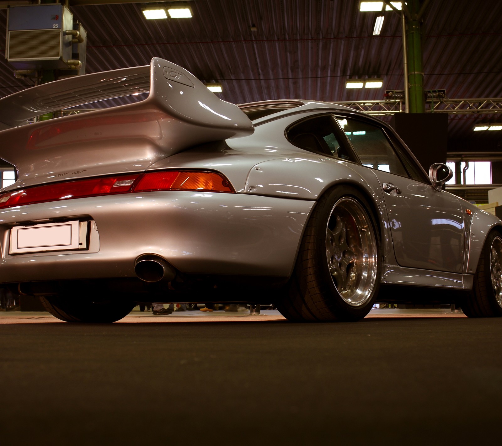 Uma visão árabe de um carro esportivo prateado estacionado em uma garagem (911, carro, corrida, carrera, clássico)