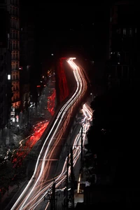 Paisaje urbano a medianoche: luces automotrices rojas y blancas cortando la oscuridad