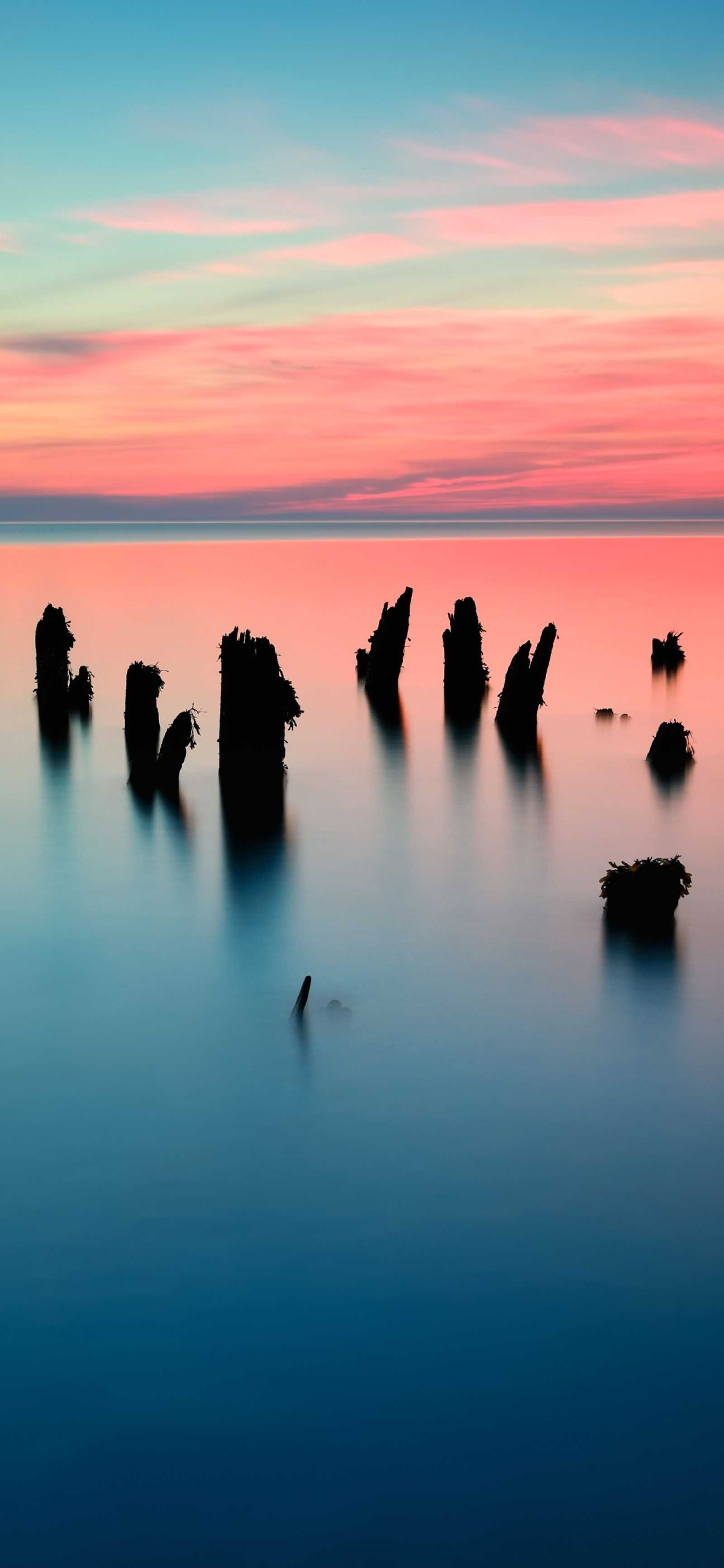 Arafed view of a body of water with a few rocks in the water (water, cloud, water resources, atmosphere, natural landscape)