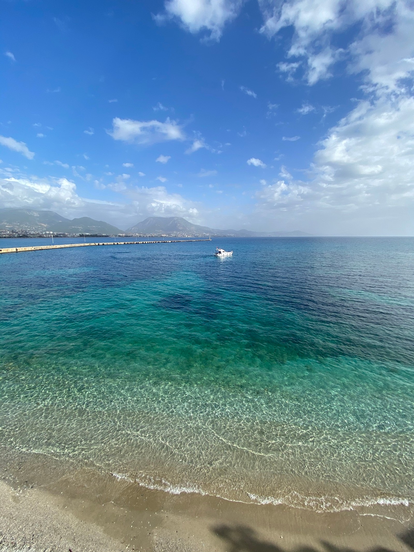 Il y a un bateau qui flotte dans l'eau près de la plage (mer, nuage, eau, bleu, azur)