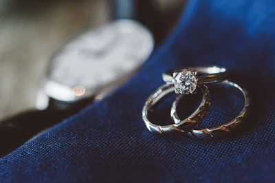 Anillos de boda de diamantes plateados elegantes sobre tela azul