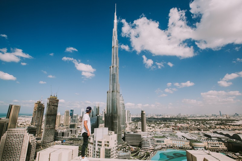 Мужчина стоит на вершине высокого здания с видом на город (burj khalifa, башня, небоскреб, достопримечательность, городская территория)