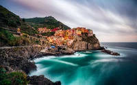 Lebhaftes Küstendorf Manarola mit Blick auf ruhige Gewässer und dramatische Klippen