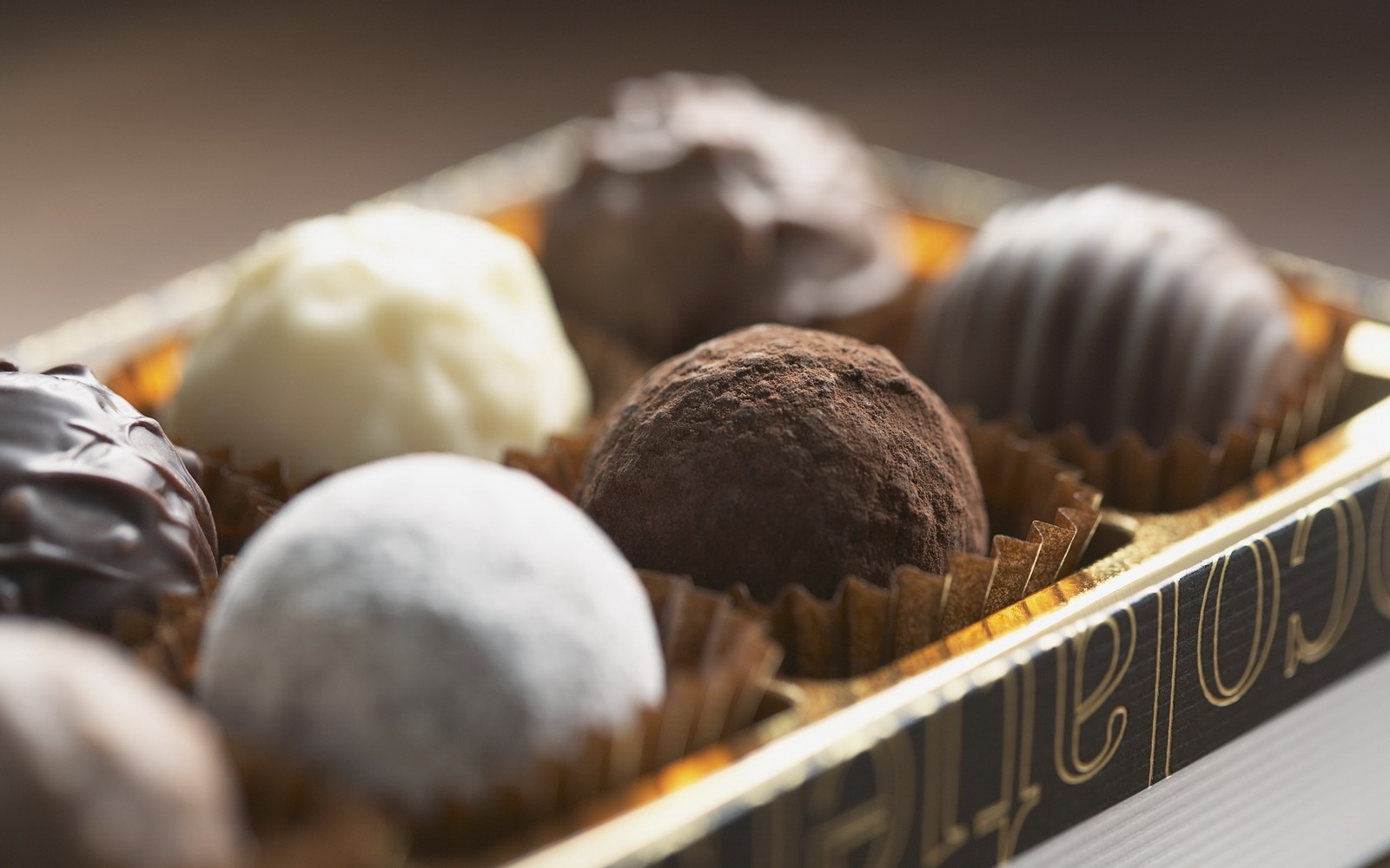 There are a box of chocolates that are sitting on a table (chocolate truffle, white chocolate, food, praline, baking)