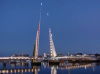 Beleuchtete Klappbrücke mit hohen Türmen in der Dämmerung über der Stadtsilhouette