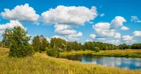 Serene River Landscape with Lush Vegetation and Puffy Clouds