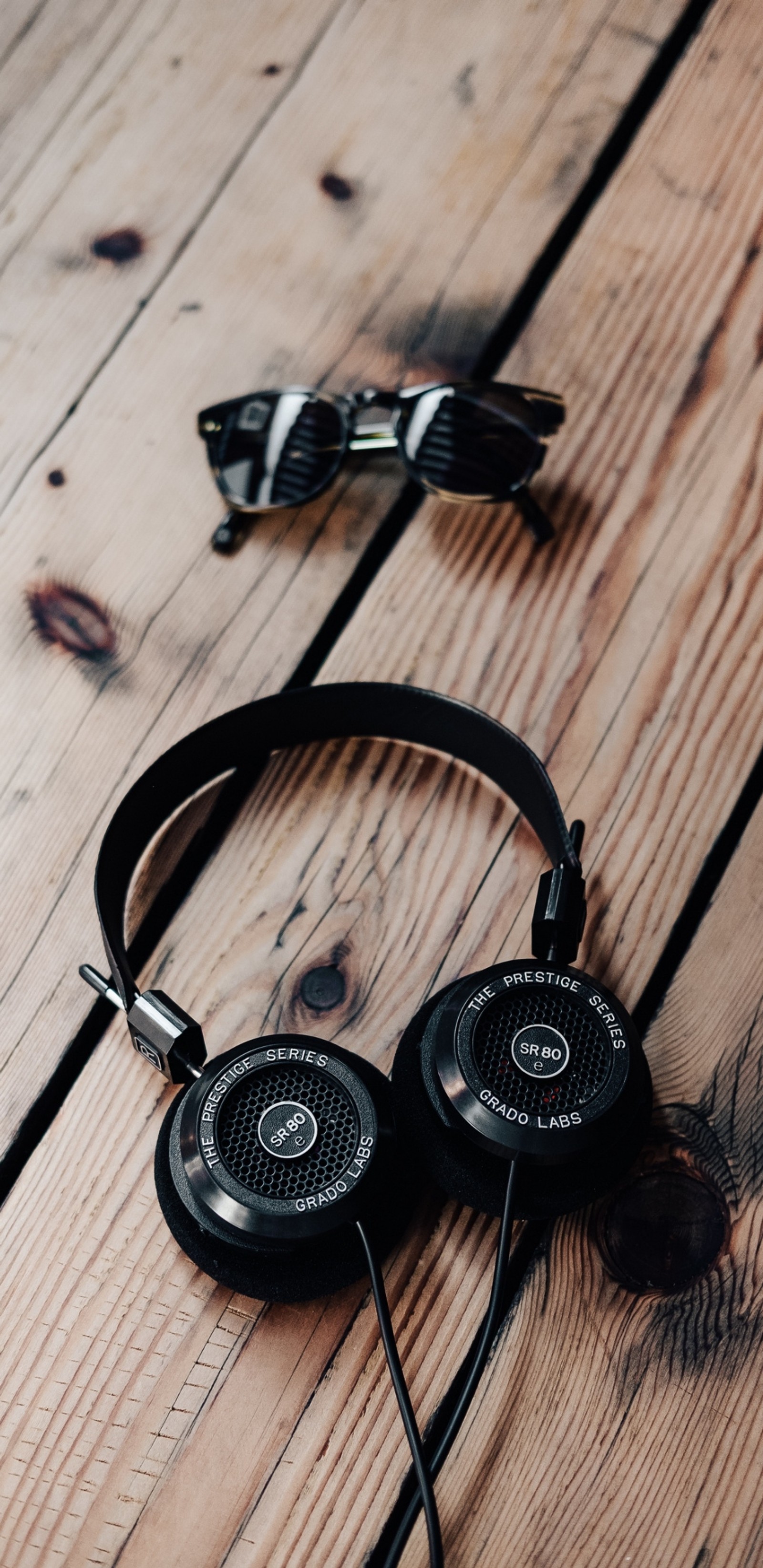 There is a pair of headphones and sunglasses on a wooden table (forever, gentleman, live, love, love forever)