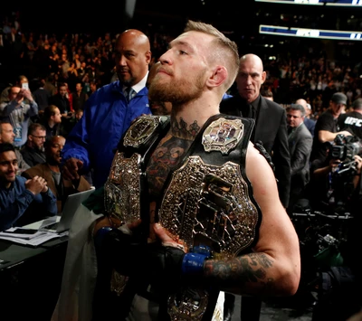 Conor McGregor célèbre avec des ceintures de champion lors d'un événement UFC