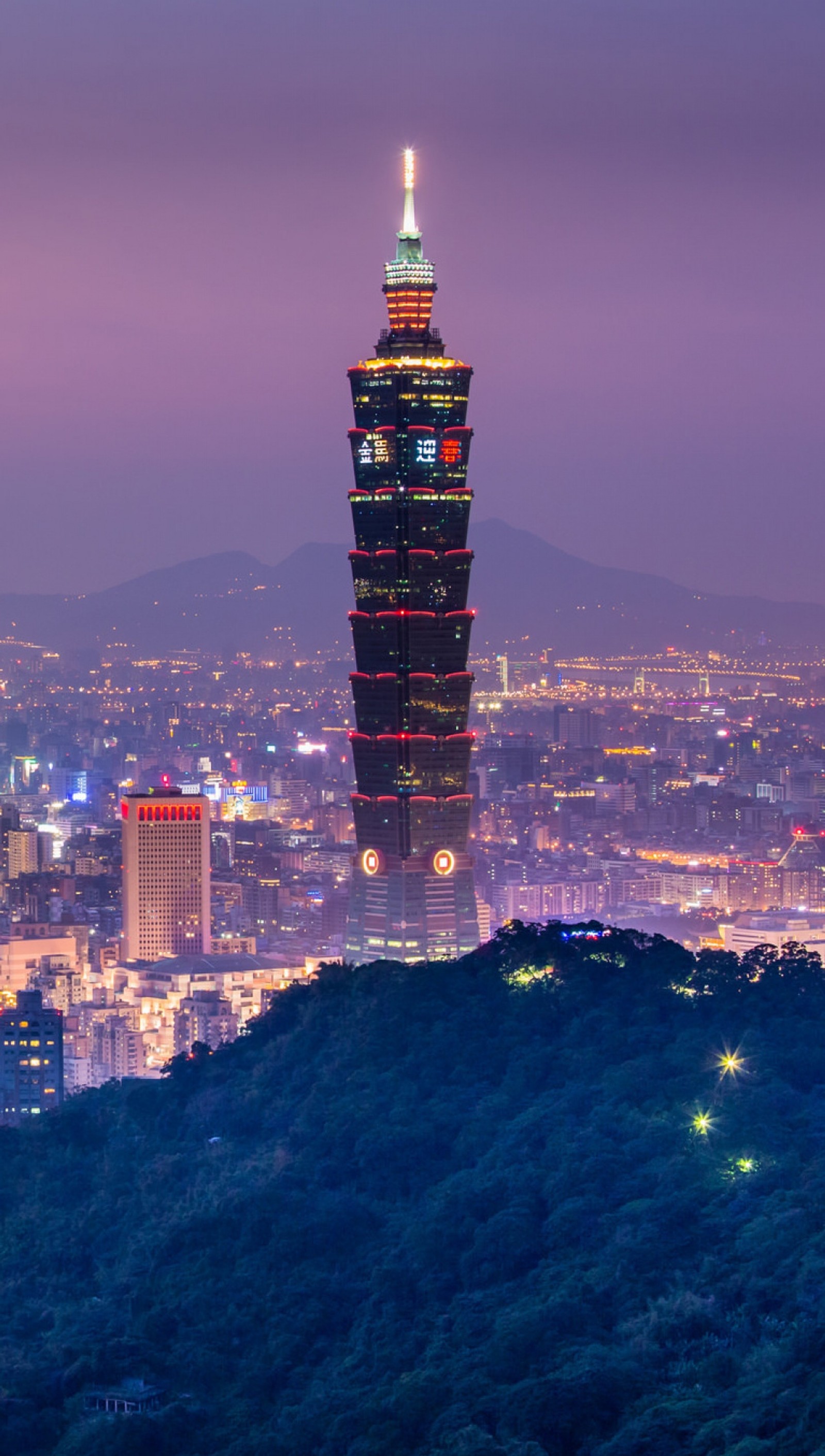 Vista aérea de uma cidade à noite com uma torre alta (ptqw, qrtw)