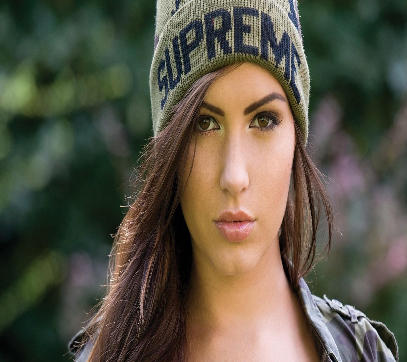 Una mujer con cabello largo y marrón usando un sombrero verde. (hermoso, lindo, niña)