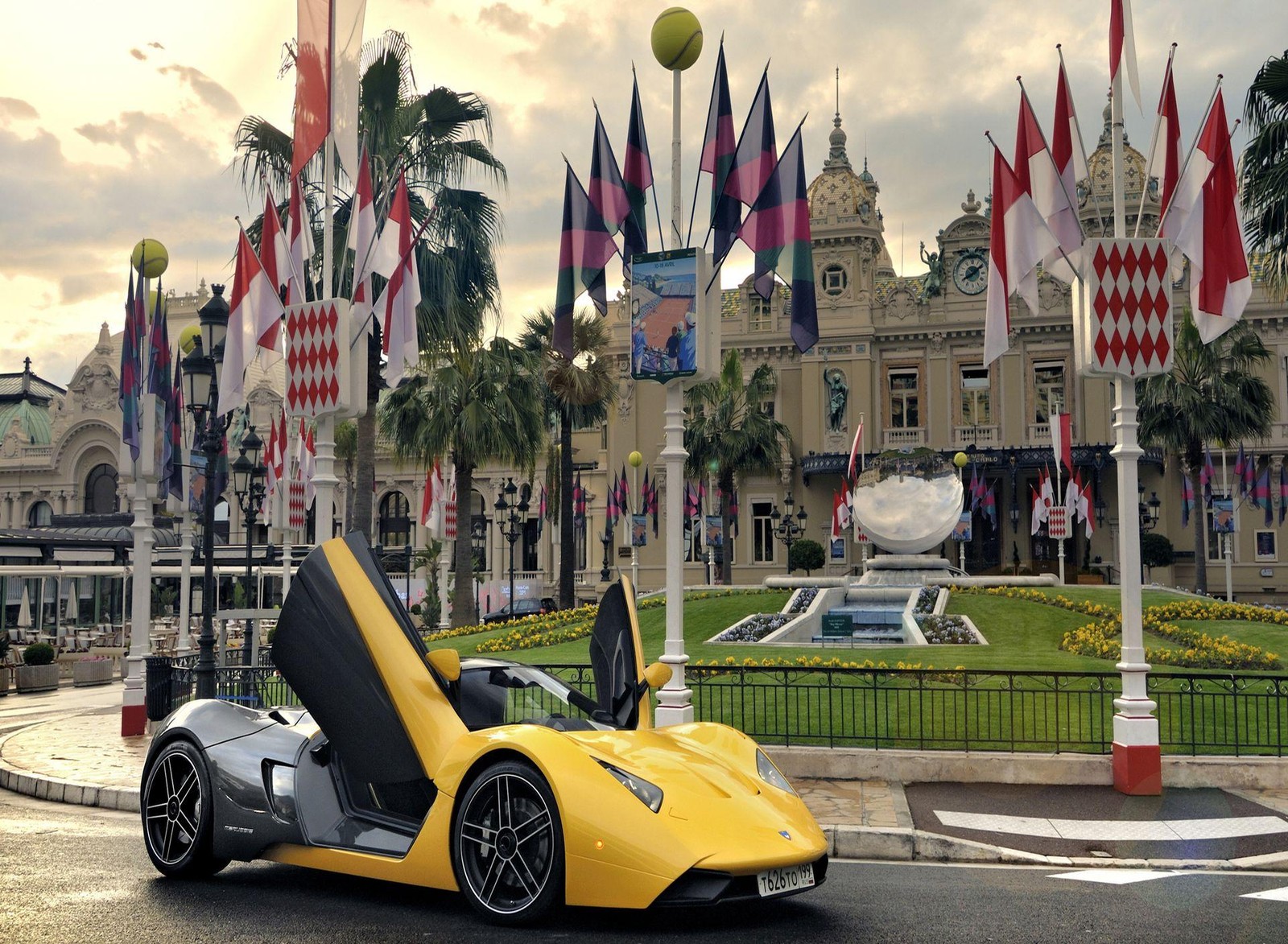 Une voiture de sport jaune garée devant un grand bâtiment avec des drapeaux (voiture rapide, courses, sport cat)