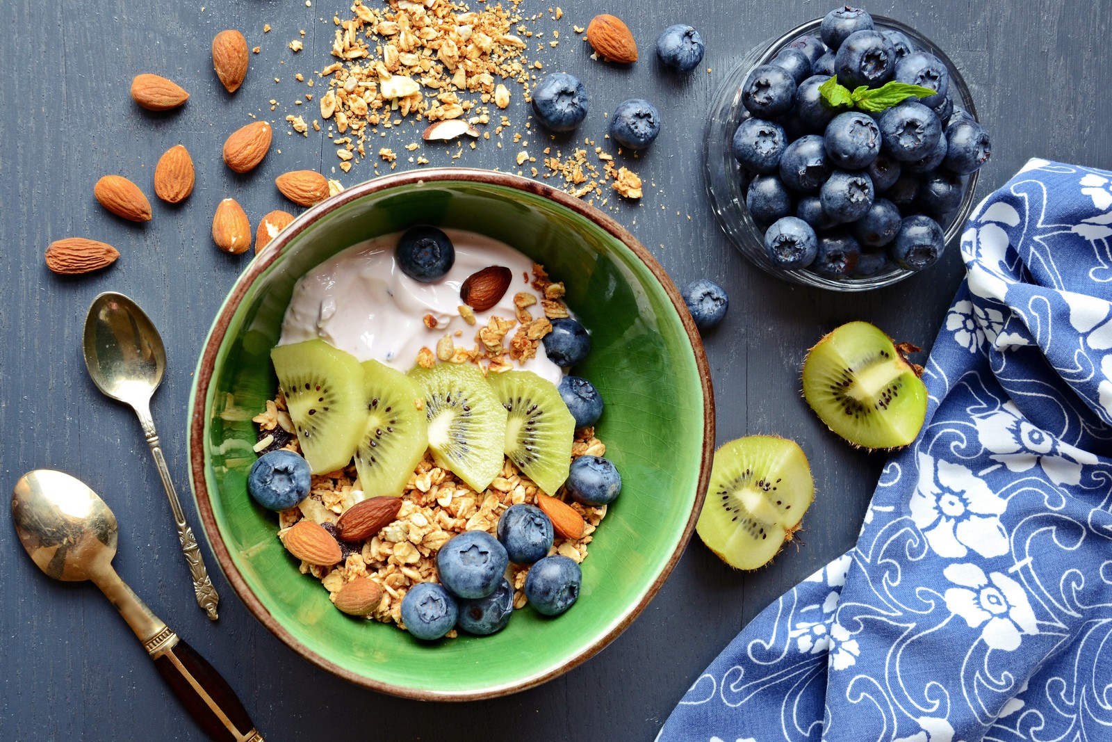 There is a bowl of granola with kiwi and blueberries (breakfast, muesli, health, fruit, eating)