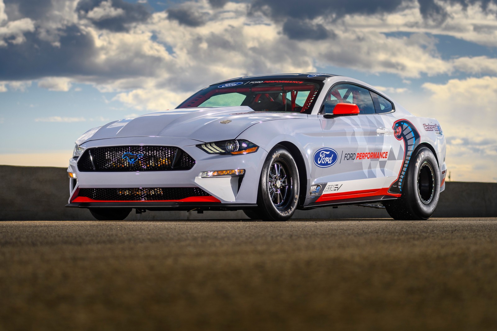 A white mustang driving down a road with a cloudy sky in the background (ford mustang, 2020, 5k, cars, 4k wallpaper)