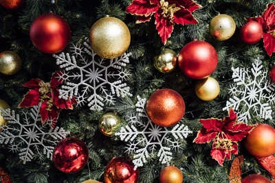 Árbol de Navidad vibrante adornado con adornos rojos y dorados, copos de nieve y festivas poinsettias.