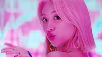 Chaeyoung do TWICE em uma iluminação rosa vibrante, exibindo uma expressão brincalhona.