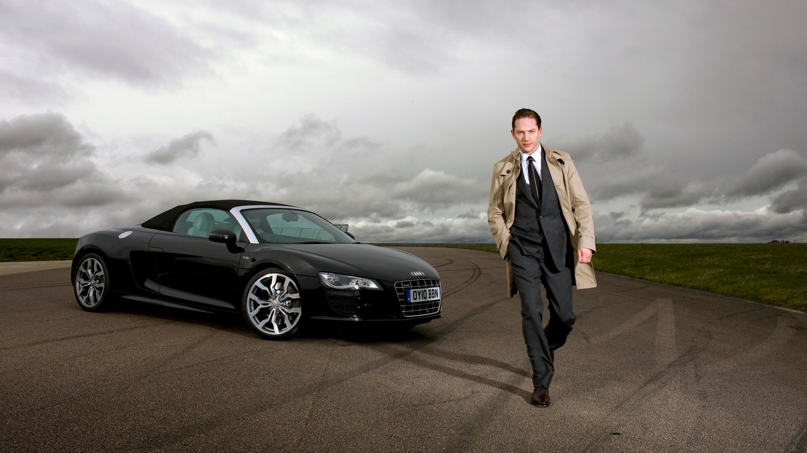 Arafed man in a suit walking towards a black sports car (tom hardy, actor, car, audi, sports car)