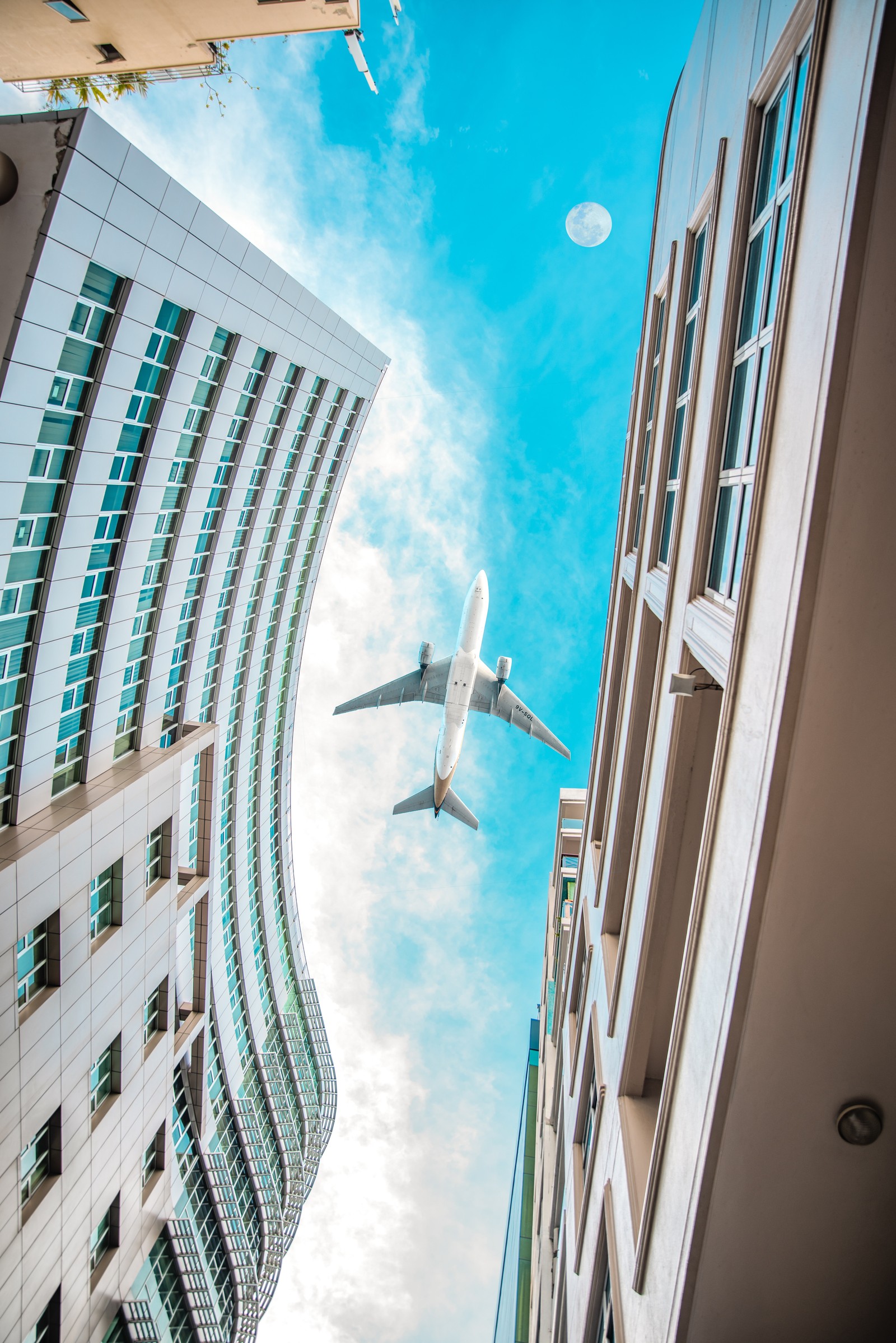 Un avion survolant une ville avec de grands bâtiments (bâtiment, bleu, architecture, chambre, ville)