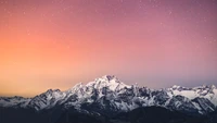 Montagnes majestueuses couvertes de neige sous un ciel étoilé au crépuscule