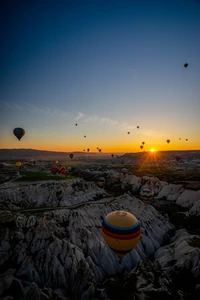 Balões de ar quente coloridos subindo contra um nascer do sol em uma paisagem natural