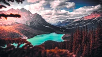 Lago de montaña vibrante rodeado de bosques exuberantes y nubes dramáticas