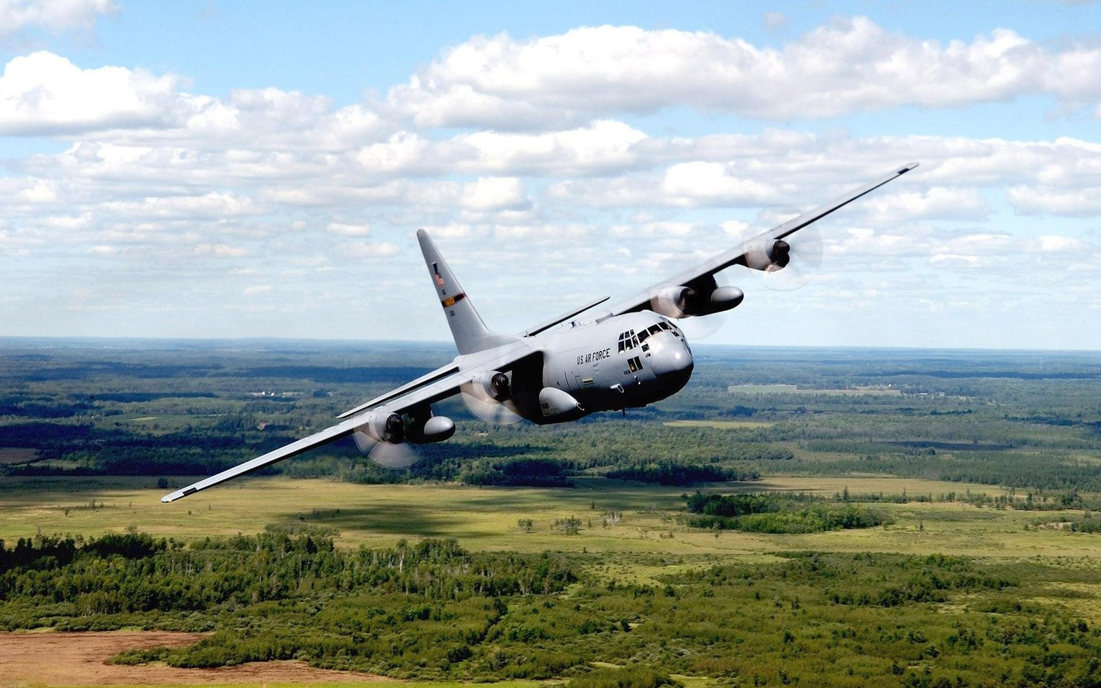 Um arafplane voando sobre um campo com árvores e um céu azul (avião de transporte militar, aeronave militar, viagem aérea, engenharia aeroespacial, força aérea dos estados unidos)