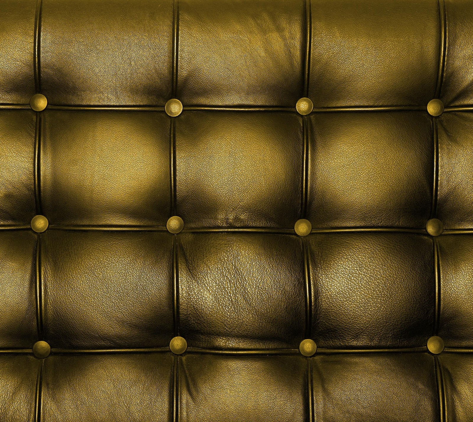 A close up of a gold leather couch with buttons (gold, leather, square)