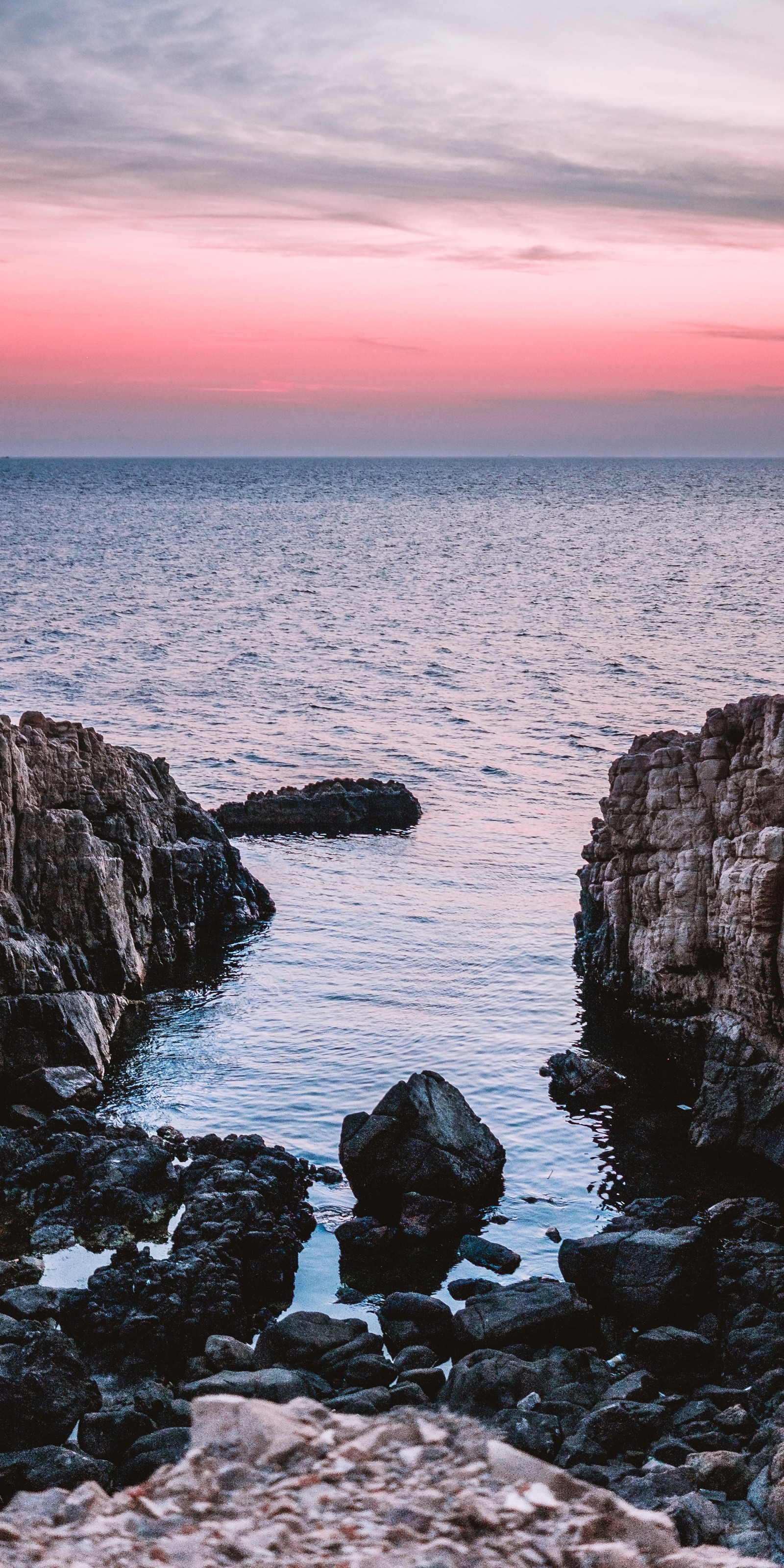 Il y a une vue sur un plan d'eau avec des rochers au premier plan (ios, eau, nuage, ressources en eau, azur)