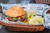 Delicioso hambúrguer com coberturas frescas servido ao lado de batatas fritas crocantes em uma cesta rústica.