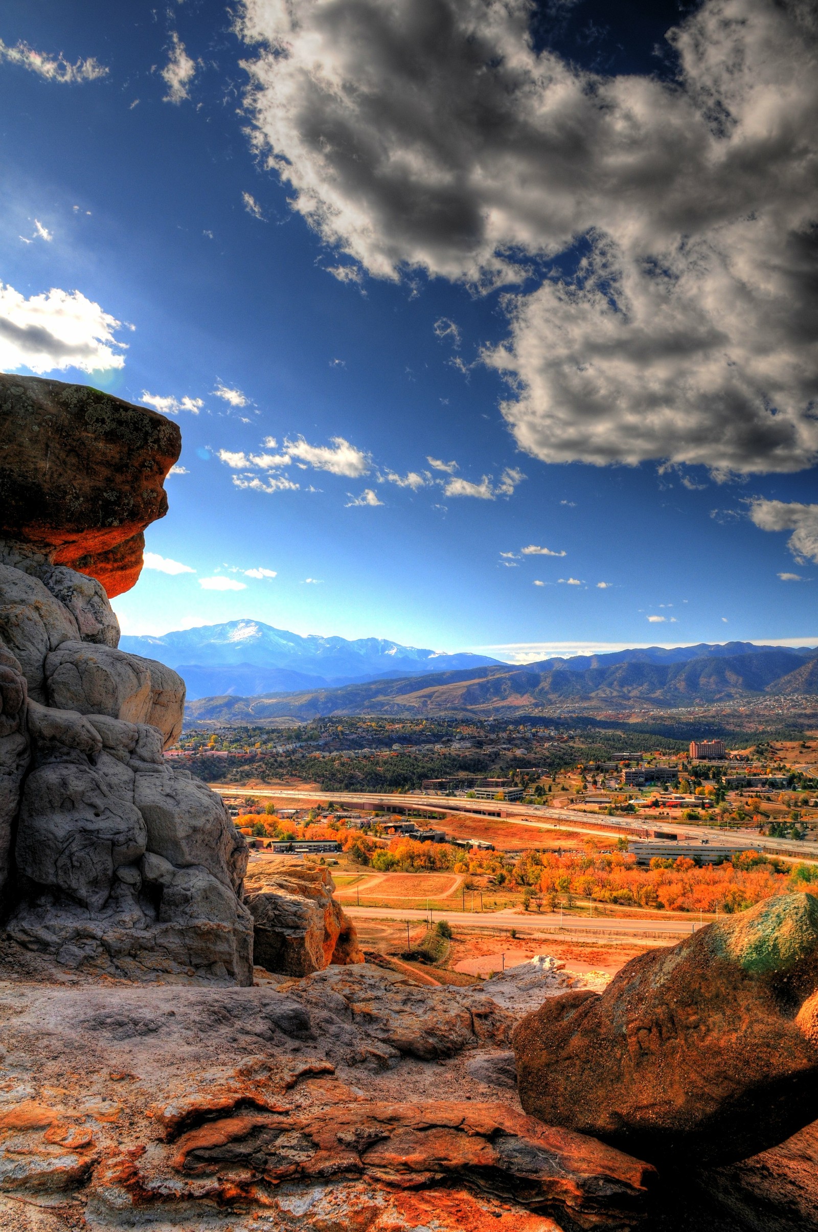 There is a large rock formation on the side of a mountain (cloud, atmosphere, ecoregion, plant, mountain)