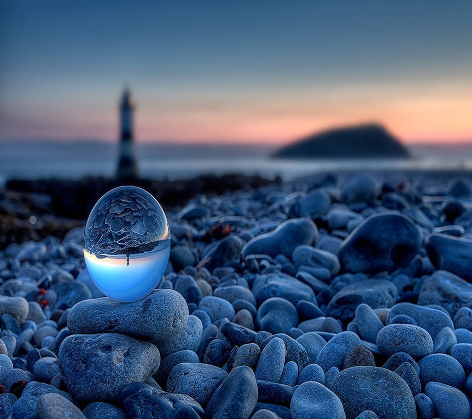 There is a glass ball sitting on a pile of rocks (beautiful, landscape)