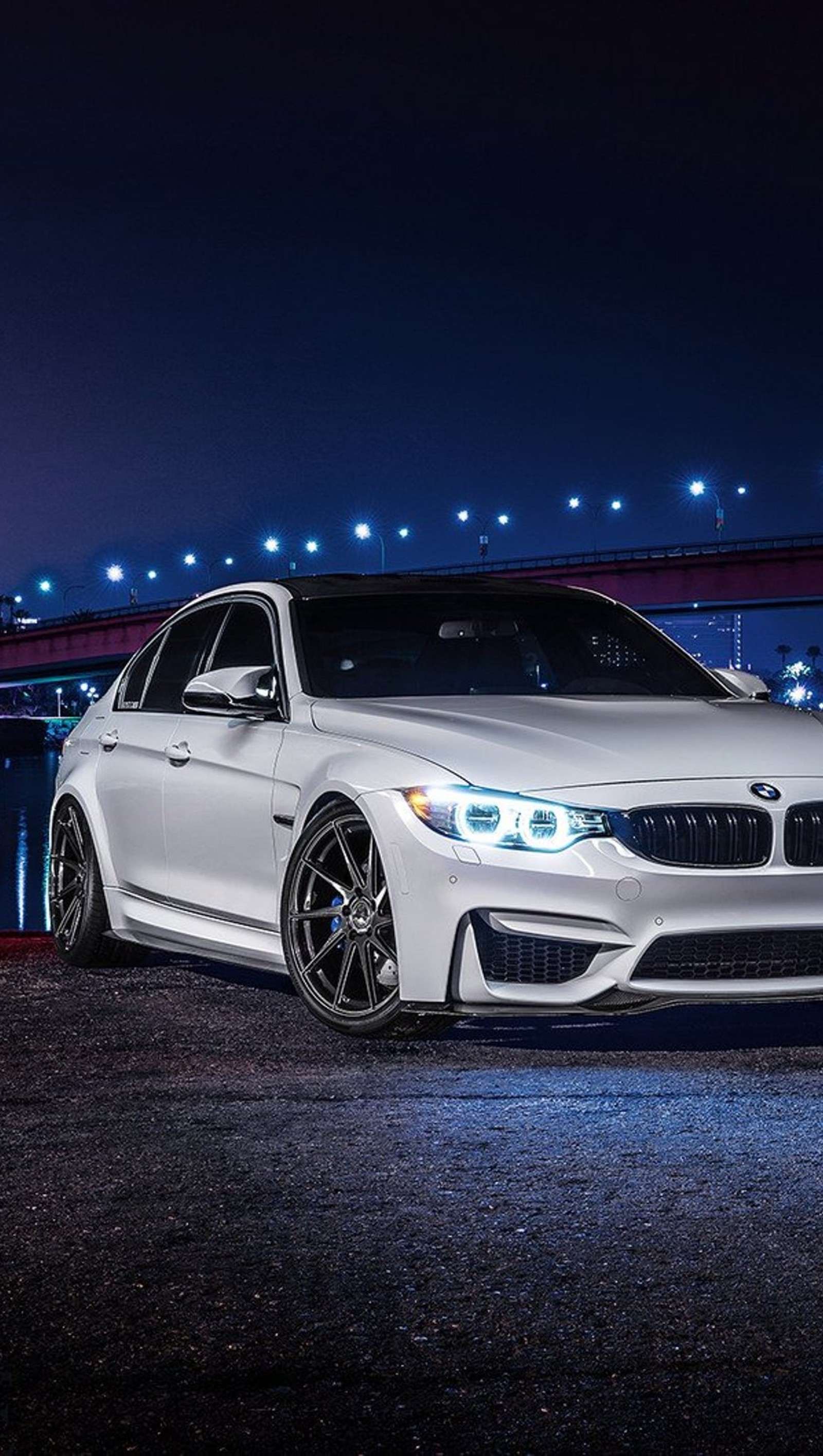 A close up of a white bmw car parked in front of a bridge (bmw, car, night, white)