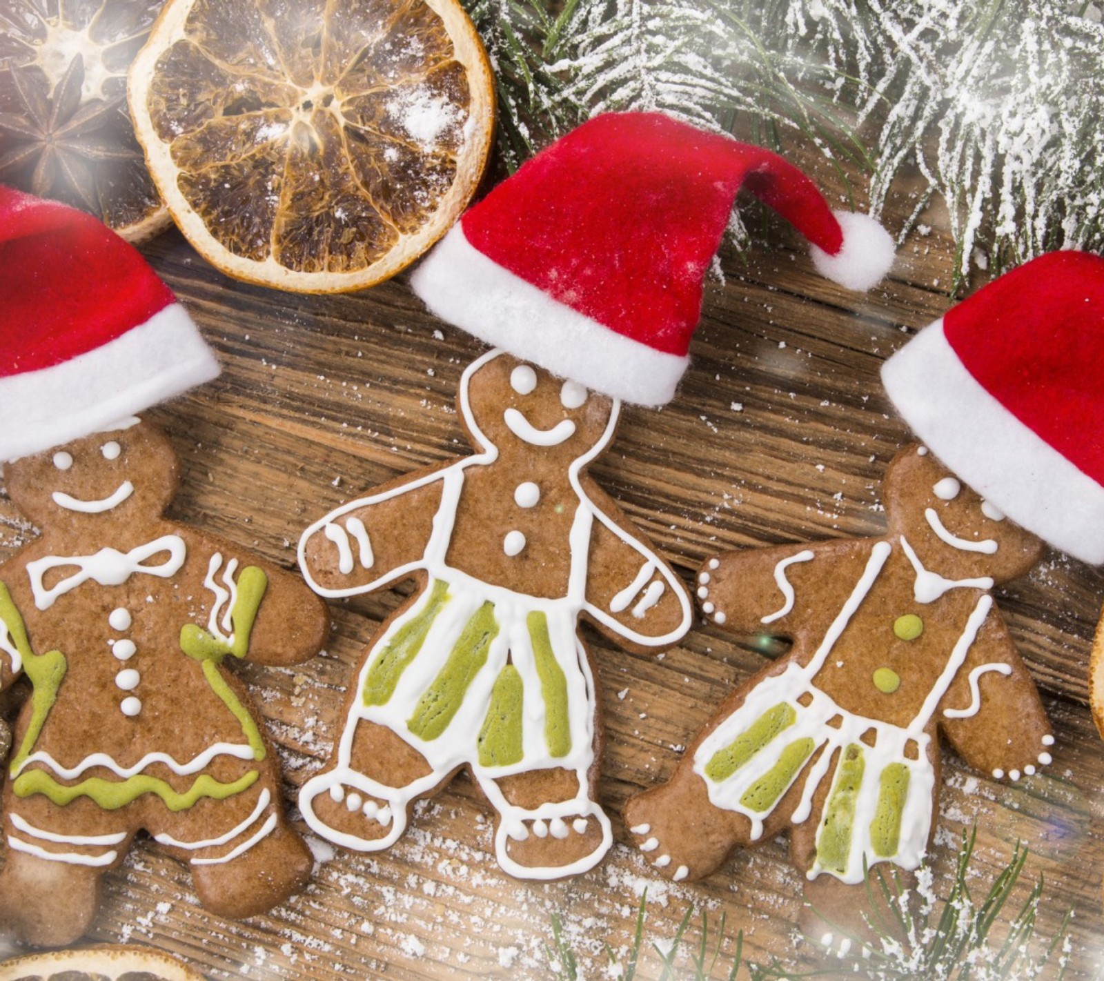 Três biscoitos de gengibre decorados com cobertura e chapéus de papai noel (enfeite de natal, pão de gengibre)